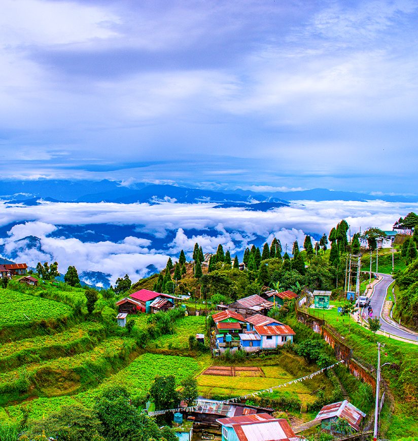 Darjeeling hill village above the clouds — tea terraces, red-roofed houses and Himalayan views